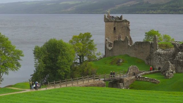 Ruins of a Scottish Castle and Tourists on the Lake