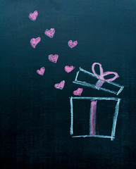 Gift box on a chalkboard with flying hearts: Creative Love and Valentine's day gift concept.