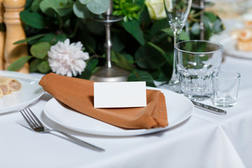Wedding table setting with blank guest card, napkin, succulent and dish on a wooden plate. Rustic...