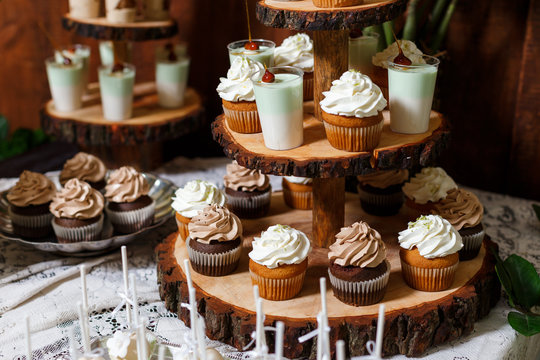 Candy bar on wooden wedding party with a lot of different candies, cupcakes, souffle and cakes. Decorated in brown and green colors, nature and eco theme, indoor