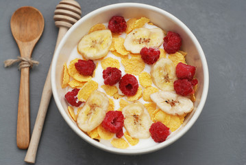 Bowl of Granola Cereals with Yogurt or Milk on Gray Background with wooden Spoon and Honey. Morning Breakfast.