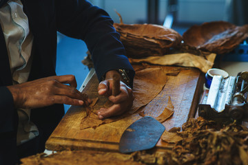 Process of making traditional cigars from tobacco leaves with own hands using a mechanical device and press.