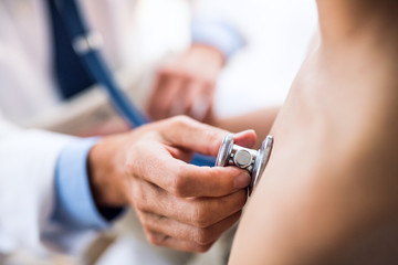 Senior doctor examining a small boy in his office. © Halfpoint