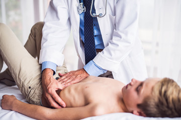 Senior doctor examining a small boy in his office. © Halfpoint