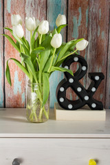 White tulips in glass jar. Wooden background.