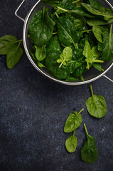 Fresh green spinach leaves on a dark concrete background, top view, flat lay, copy space.