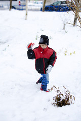 Fototapeta na wymiar Portrait of cute little boy playing with snow in winter