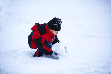 Fototapeta na wymiar Portrait of cute little boy playing with snow in winter
