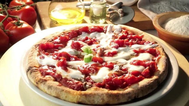 Pizza with tomato mozzarella cheese and anchovies on the table