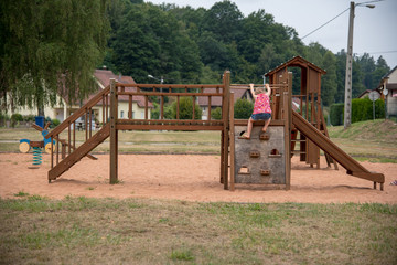 Fototapeta na wymiar Girl climbing on wooden public games, France.