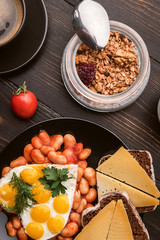 English breakfast. sausage, fried eggs and beans in tomato. coffee and bread nearby. chia with yogur and granola