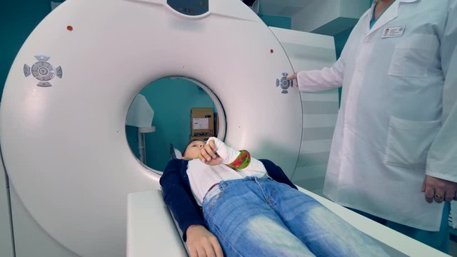 A doctor controls a boys CT scan. 