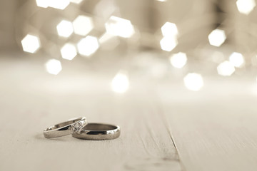 Two wedding rings place on wooden floor with light bokeh background. - obrazy, fototapety, plakaty