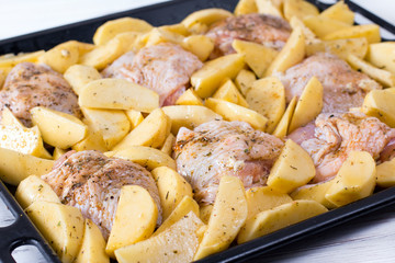 Raw chicken with raw potatoes in the form for baking, ready to be cooked