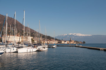 Il porto con le barche sul lago di Garda sullo sfondo della montagna innevata