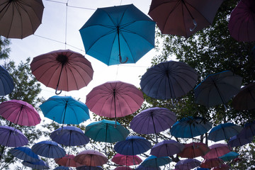 Fototapeta na wymiar Silhouette of colorful umbrellas hanging above the street