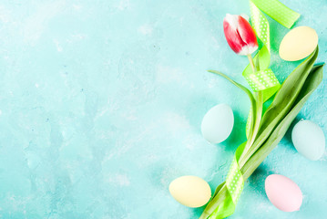 Multicolored Easter eggs with tulips flowers on a light blue background,copy space top view