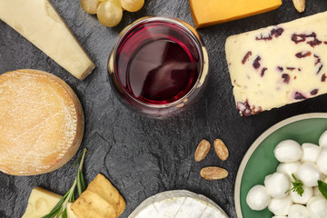 Various types of cheese with wine on black with copy space