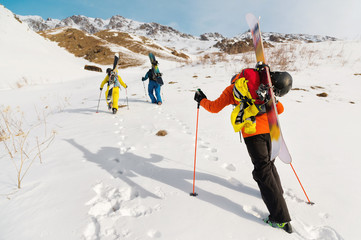 A group of three freeriders climb the mountain for backcountry skiing along the wild slopes of the