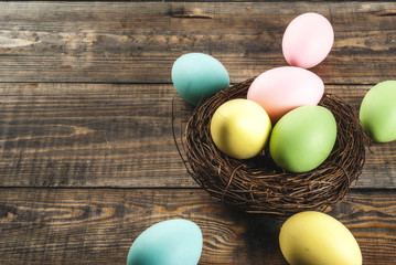 Multicolored Easter eggs in bird's nest on wooden background,copy space top view