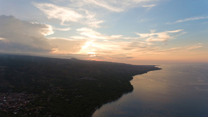 Sea coast at sunset. Aerial view of sunset on the ocean coast, mountains, sea, beach, sky, clouds. Bali, Indonesia. Sunset on the island of Bali.