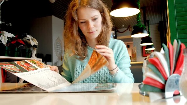 Woman in a cafe. Woman looks at the menu in a cafe
