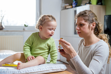 Mother giving sick child a syrup