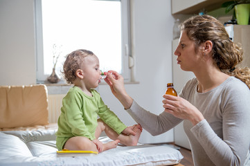 Mother giving sick child a syrup