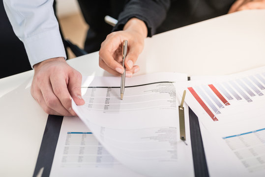 Business man and woman analyzing statistical bar graph and financial reports at desk in the office