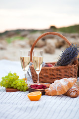 Two glasses of champagne. Picnic on the beach at sunset in the white plaid, food and drink...