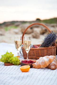 Two glasses of champagne. Picnic on the beach at sunset in the white plaid, food and drink conception