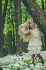 Naklejka premium lovely girl in white dress posing in spring forest