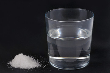 Bicarbonate de soude à côté d'un verre d'eau