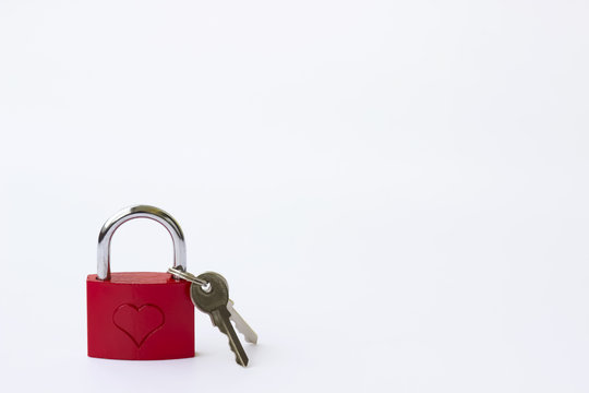 Red metal lock with a pattern in the form of a heart and keys on a white background.