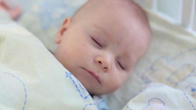 Close up of a little baby boy sleeping, baby lying in baby cot