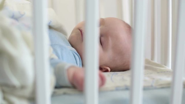 Close up of a little baby boy sleeping, baby lying in baby cot