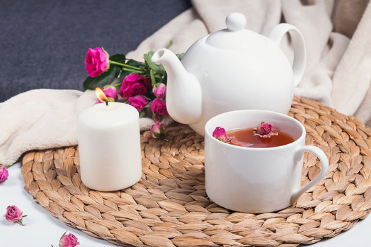Herbal tea, pink roses and teapot on the coffee table