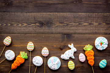 Easter background. Cookies in shape of easter bunny and easter eggs. Dark wooden background top view copy space