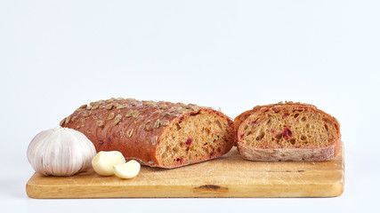 Cut bread with beets, sunflower seeds and garlic on a board.