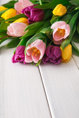 Naklejka na ściany i meble Bright tulips bouquet on white wood background, copy space