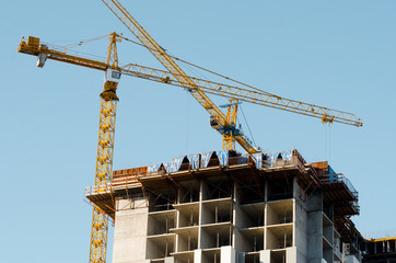 Fototapeta premium Construction cranes against the blue sky. Construction. Apartments for sale. Housewarming