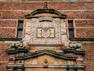 Obraz premium Hillerod, Denmark - September, 23th, 2015. Copper lion sculptures and blazon on brick wall of Frederiksborg castle near Copenhagen.