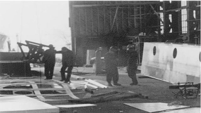 Men working inside a large building at a shipyard.