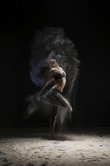 Fototapeta na wymiar Slim girl dancing in white dust cloud view