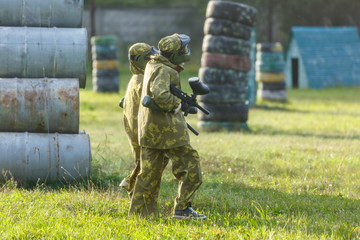 kids play paintball on special field with barrels, tires in the summer
