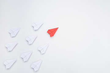 Leadership concept with red paper plane leading among white.