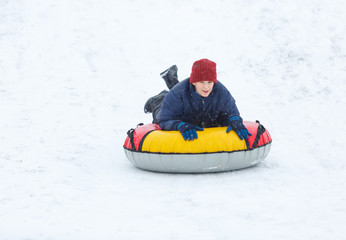 Fototapeta na wymiar kid sledding from a hill, makes snowballs and snowman on his winter holidays