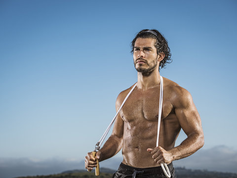 A muscular man holding jump rope