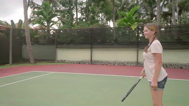 balinese tennis coach teaching caucasian teen girl to play on outdoor court