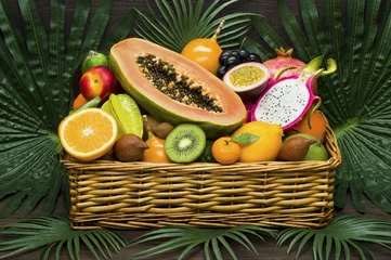 Rucksack Frische thailändische Früchte im Weidenkorb auf Palmblättern und Holzhintergrund, gesunde Ernährung, Diäternährung © antonmatveev